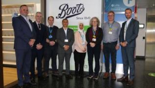 Group shot of Boots and Trust staff who have launched the new outpatient pharmacy service. A Boots sign is in the background.