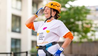 Linda Connelly at the St Thomas' abseil. Linda is wearing an Evelina London Children's Charity t-shirt and an orange helmet. 