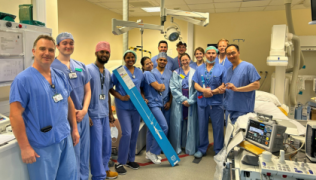 Image of hospital team involved in new pacemaker technology. They are all wearing blue scrubs with some of them wearing surgical hats.