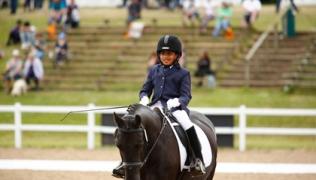 Govind, riding a horse, competing in a dressage competition.