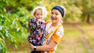 Rose carrying Molly. Rose has just ran the Royal Parks half marathon and is wearing a medal. 