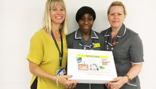 Three nurses holding up an activity box for dementia patients