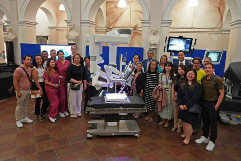 Staff in a group shot around the da Vinci robot cutting a cake to celebrate 10,000 cases