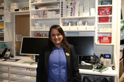 A Boots pharmacy staff member stands inside the outpatients pharmacy at St Thomas'. Medicines are in the background.