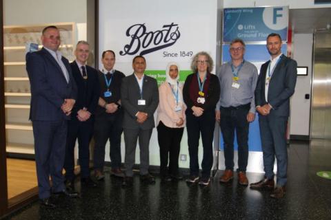 Group shot of Boots and Trust staff who have launched the new outpatient pharmacy service. A Boots sign is in the background.