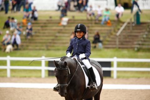 Govind, riding a horse, competing in a dressage competition.