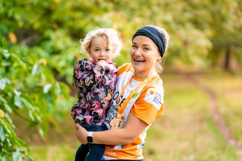 Rose carrying Molly. Rose has just ran the Royal Parks half marathon and is wearing a medal. 