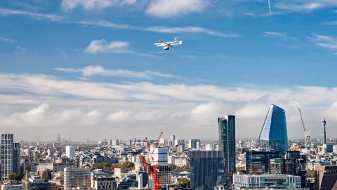 Photo of an NHS delivery drone in flight against the backdrop of a London skyline